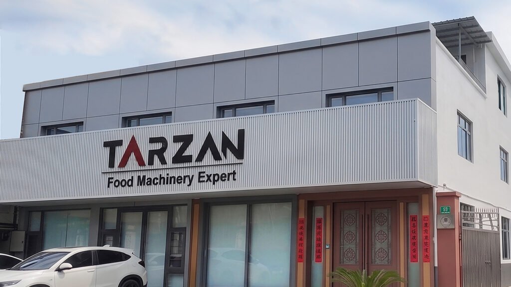Exterior view of the Tarzan Food Machinery Expert company headquarters building featuring the brand logo on the front facade